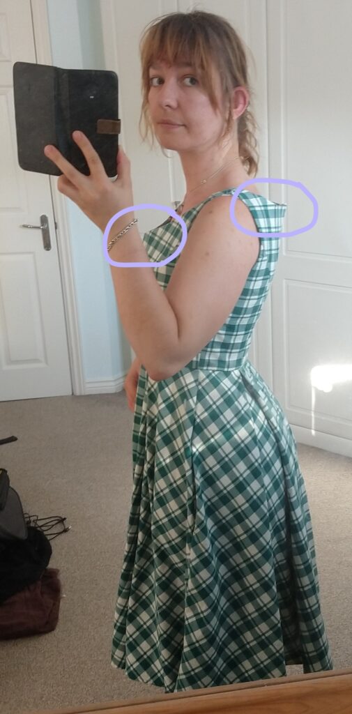 michelle models the chequered dress from the side so that the gaping at the neckline (highlighted purple) is visible